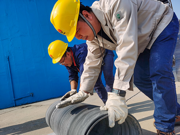 1697794787259266.jpeg 尿素車間后包裝人員劉濤、王華斌將更換下來的廢棄皮帶卷起來回收.jpg